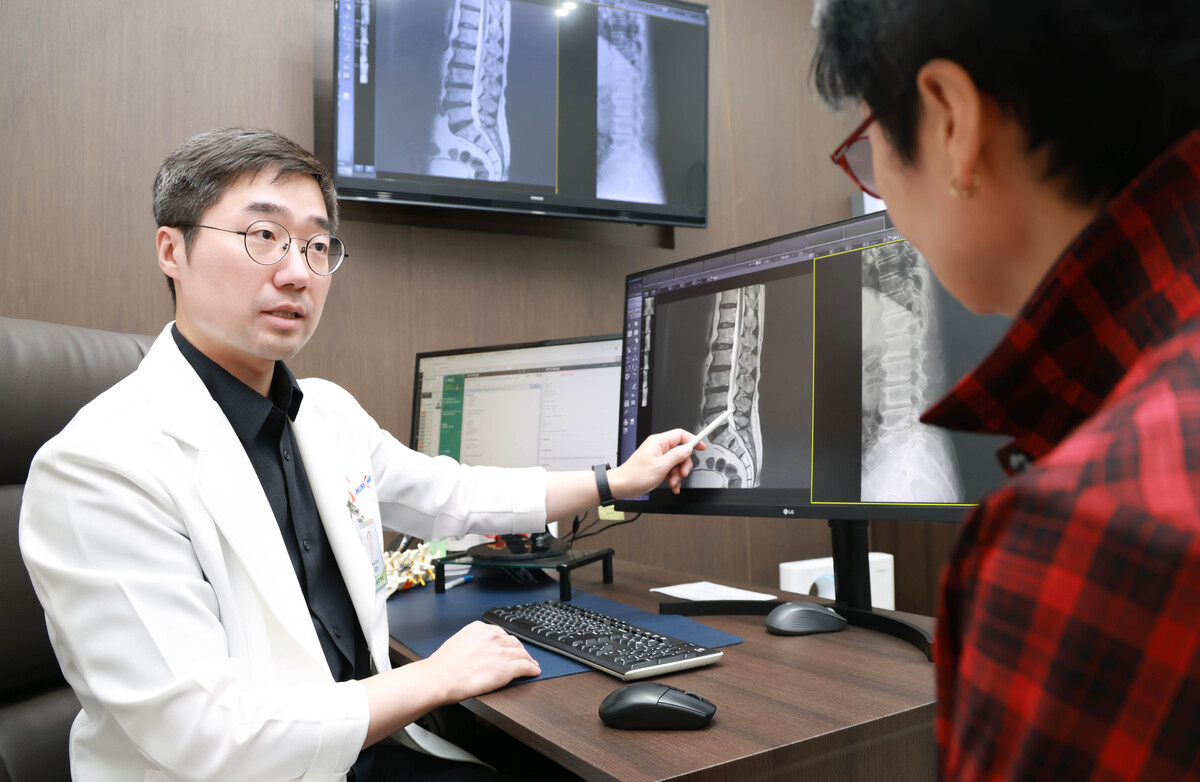 김강언 목동힘찬병원 신경외과 진료원장이 환자의 척추 영상검사 결과를 살펴보며 치료 방법을 설명하고 있다.